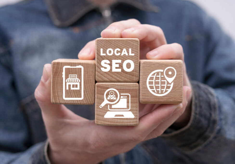 Man holding wooden cubes with icons and inscription: LOCAL SEO. Local search marketing e-commerce. Concept of local seo strategy, local search optimization.